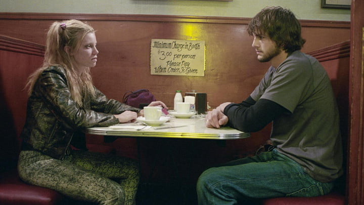 Amy Smart and Ashton Kutcher sitting across from each other in a diner booth.