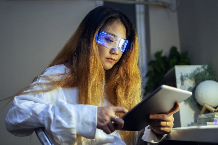 AR glasses Woman wearing augmented reality glasses checking her digital tablet.