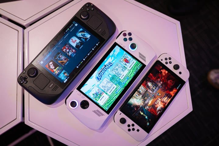 A Steam Deck, Asus ROG Ele and Nintendo Switch OLED sit on a table.
